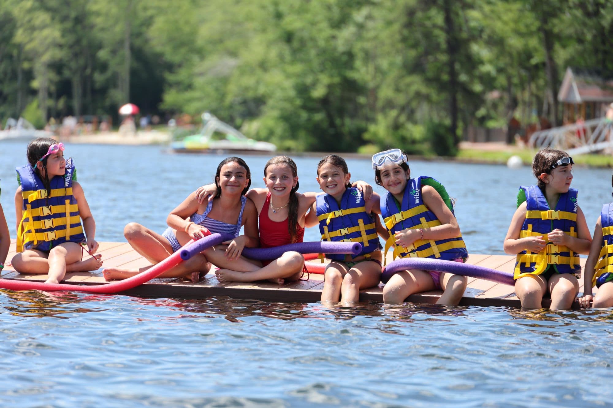 Campers in life jackets sitting together on a lake dock