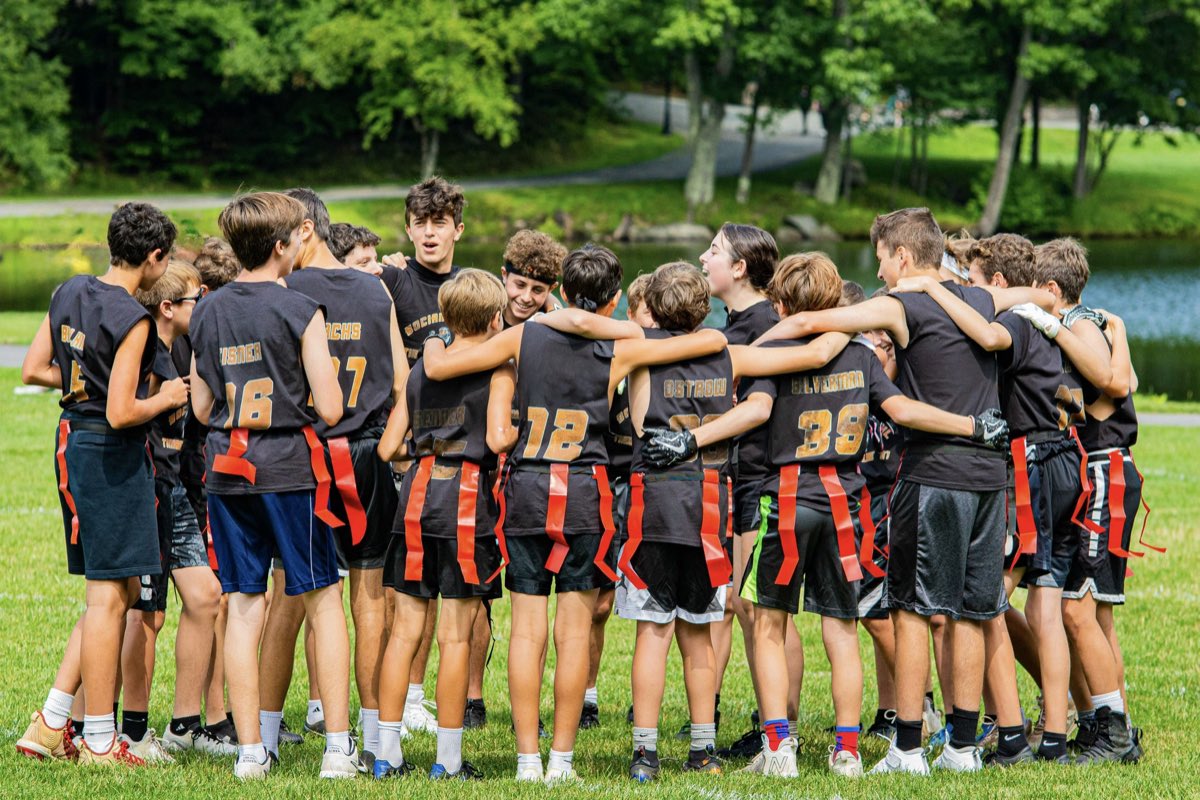 Campers in team jerseys huddled arm in arm on the field