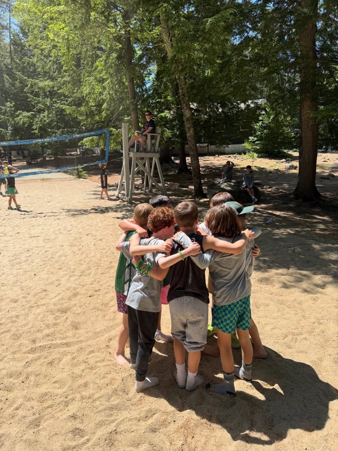 Campers huddled arm in arm on the sand court