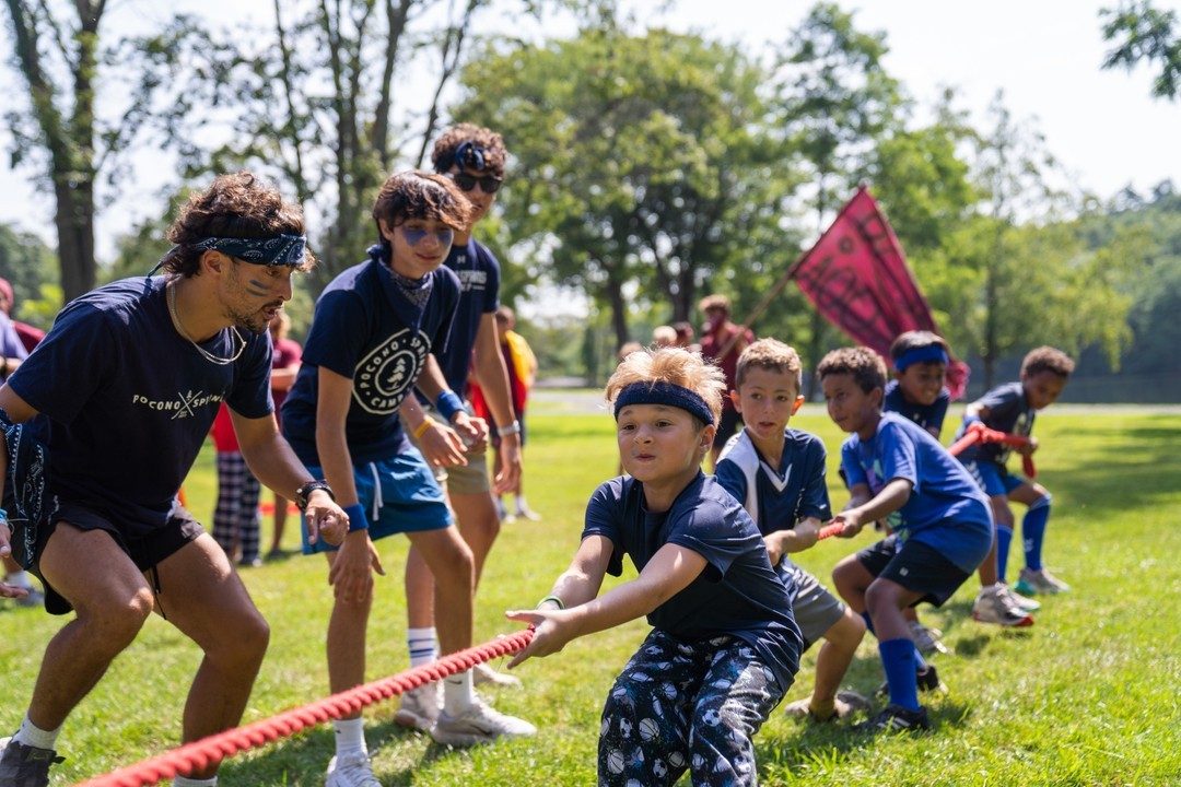 Campers heaving on the rope in a tug of war on the field