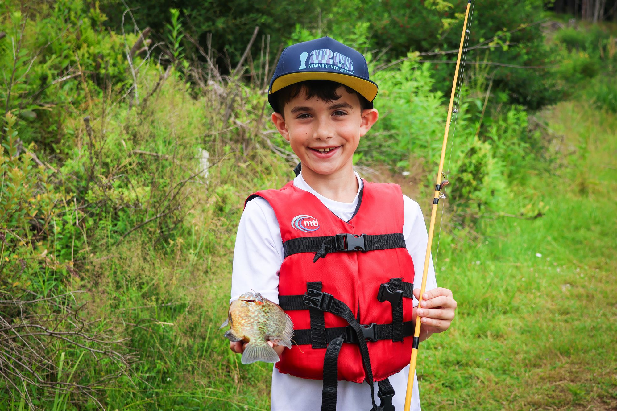 A young camper in a red life jacket smiling