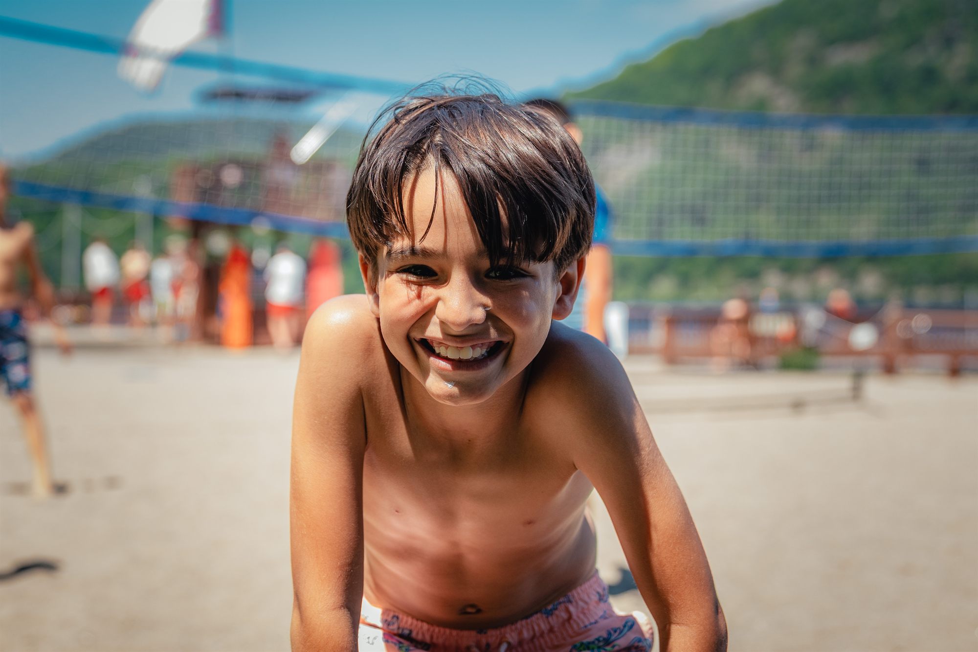 A camper grinning at the camera by the lake