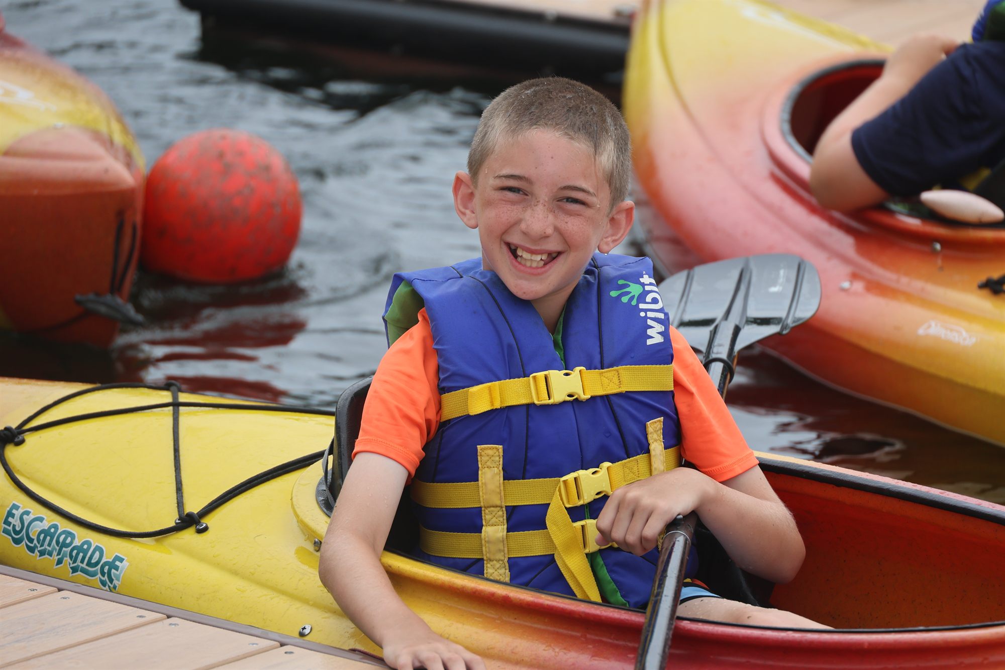 A young camper in a life jacket sitting in a kayak