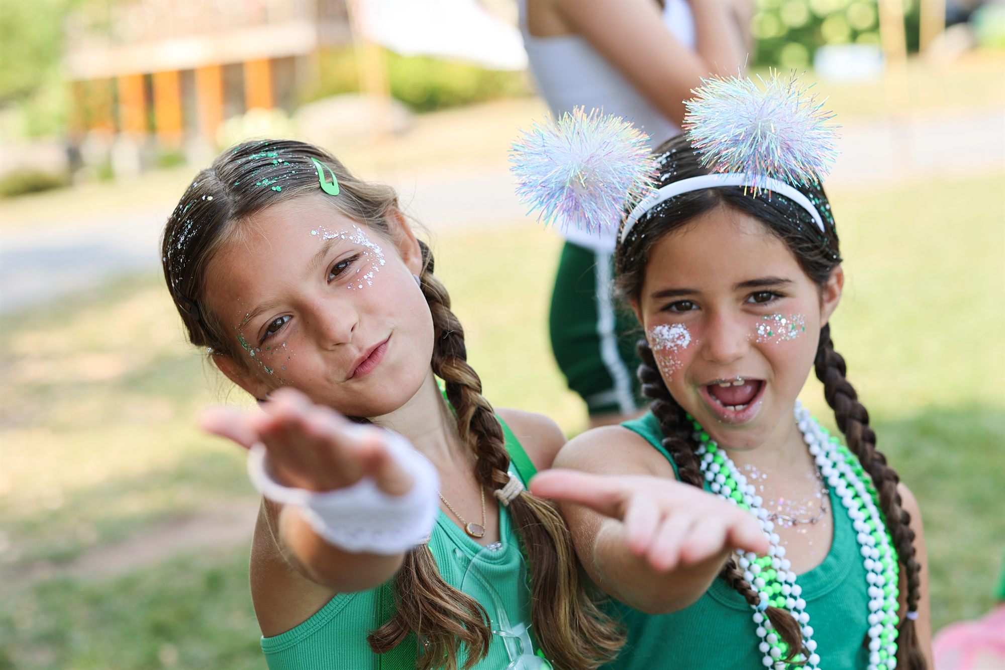 Two campers covered in glitter blowing it toward the camera