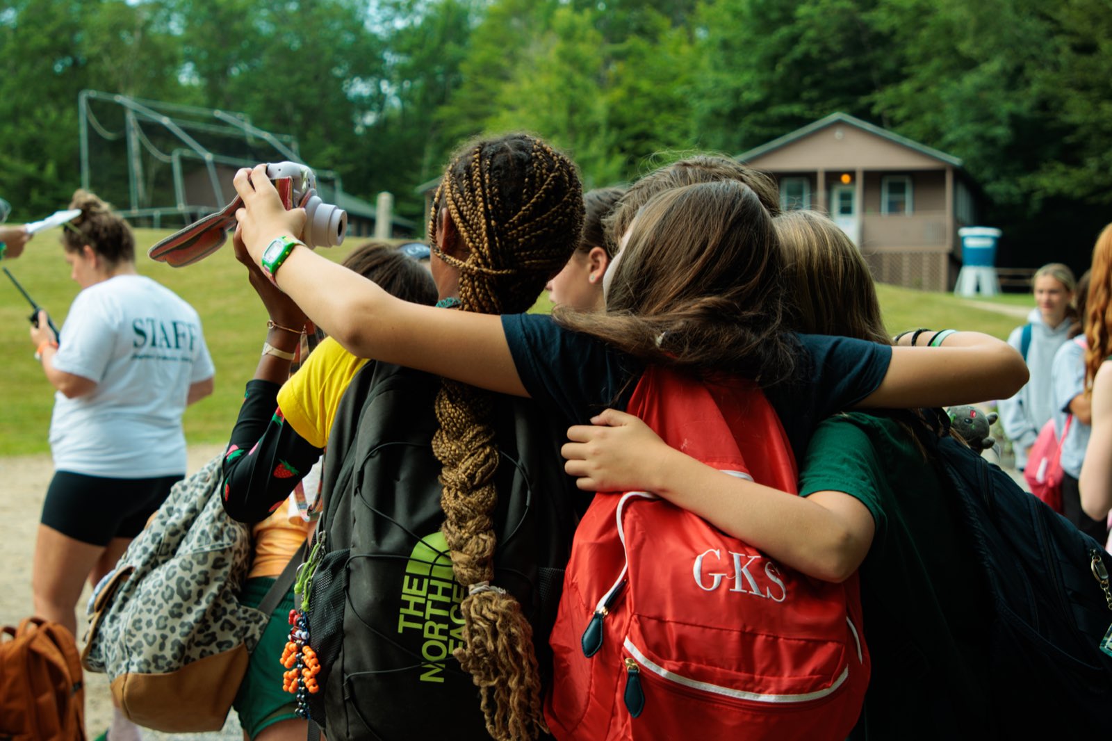 Campers with their backpacks on, arms around each other on the first day of camp