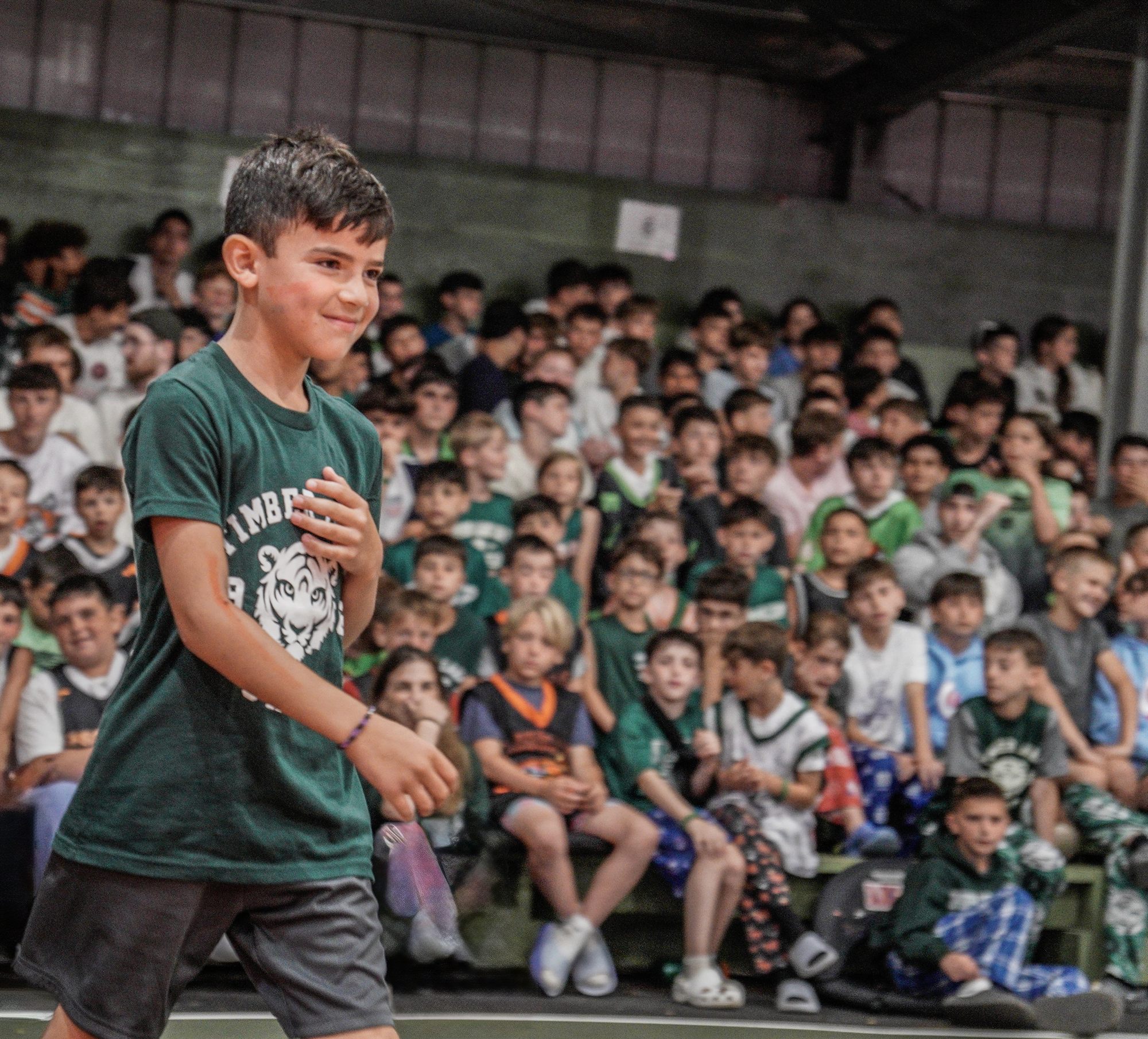A camper cheering in front of the whole camp in the gym