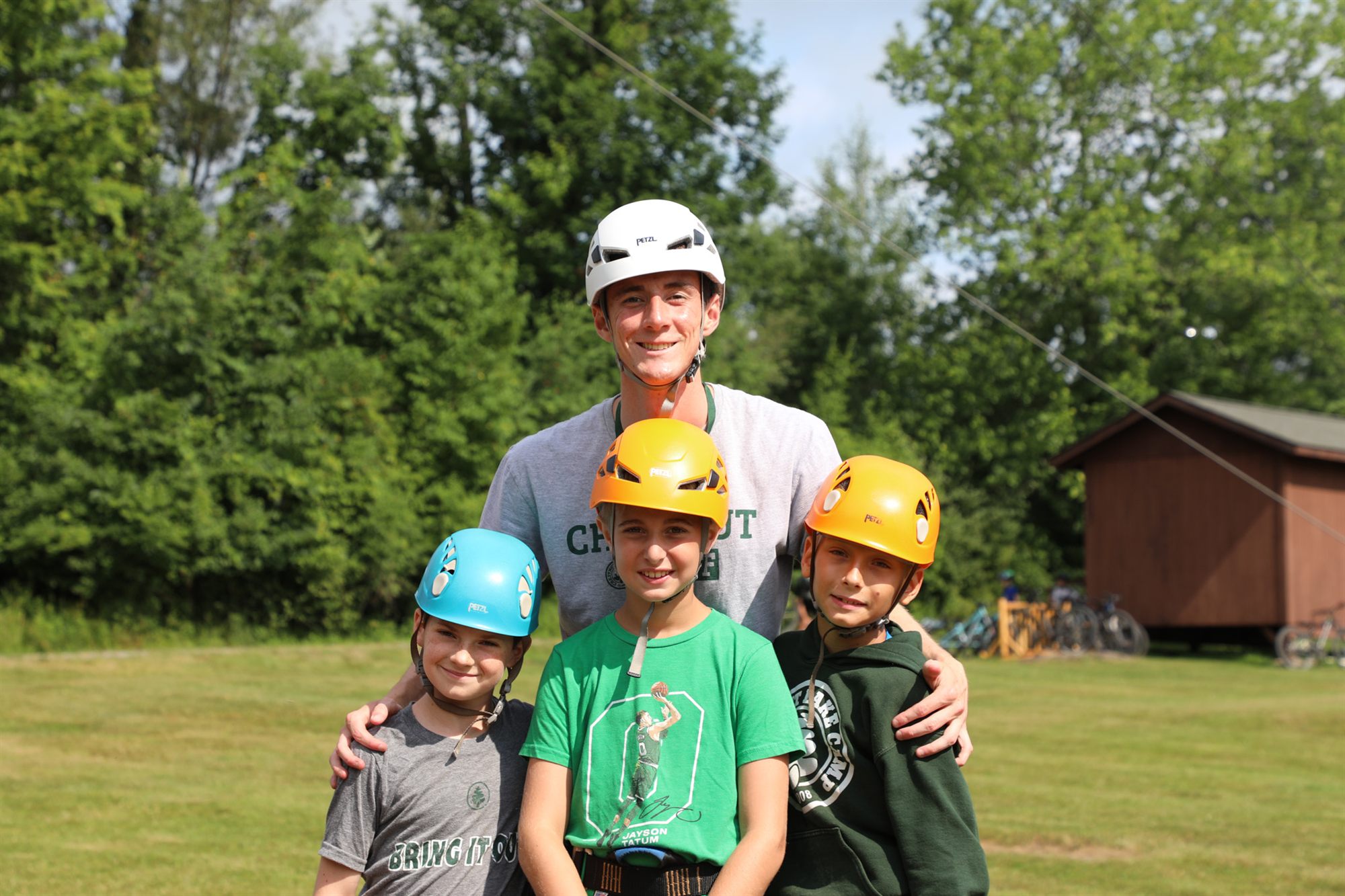 Three young campers in climbing helmets with their counselor