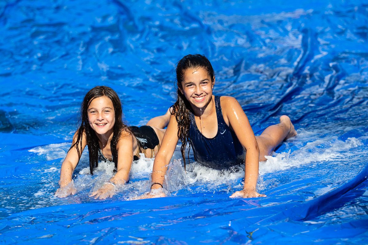 Two girls laughing on a blue slip-and-slide
