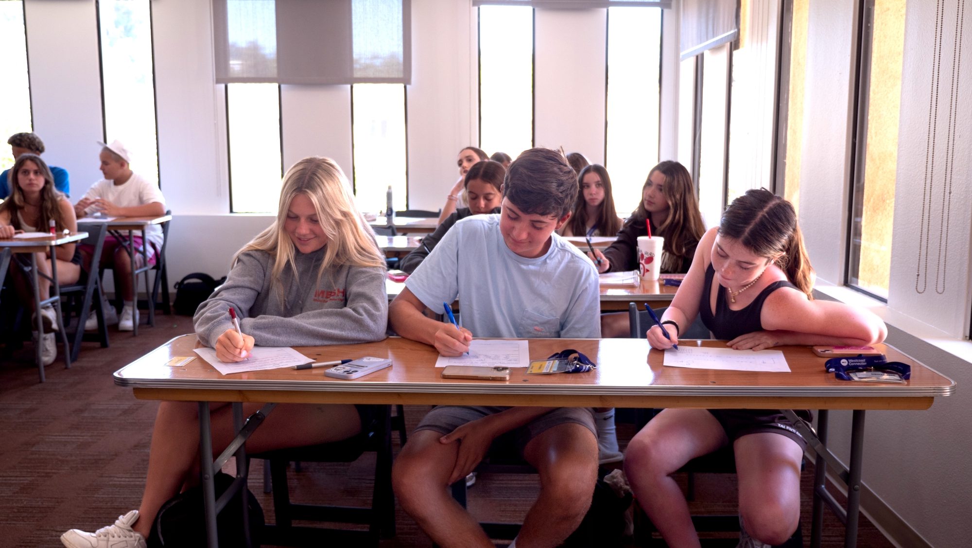 Pre-college students working at their desks in a sunlit classroom
